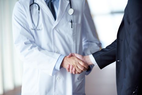 doctor handshake with a patient at doctors bright modern office in hos